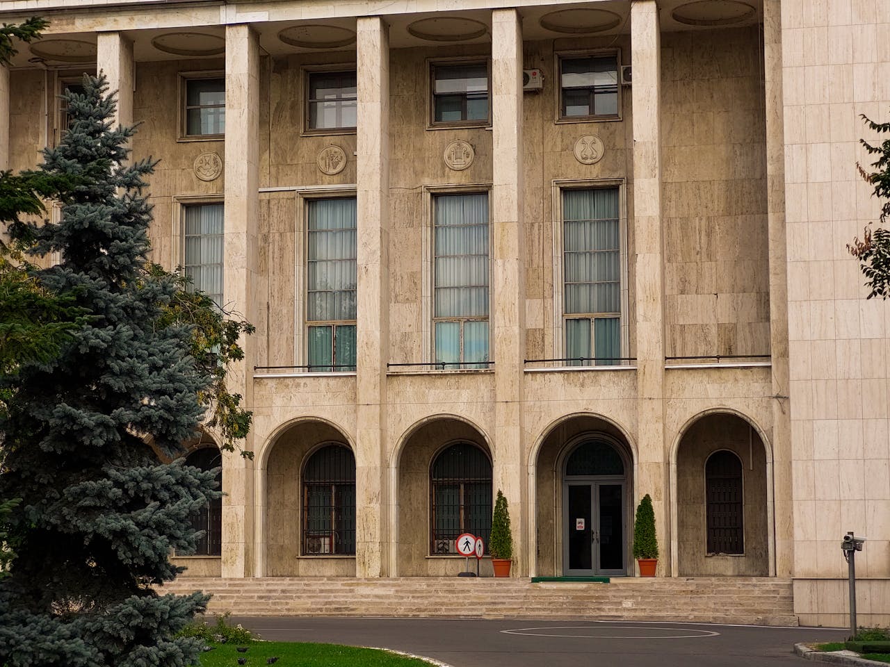 our-story Exterior of a classical building with columns, arches, and greenery, showcasing elegant architecture.